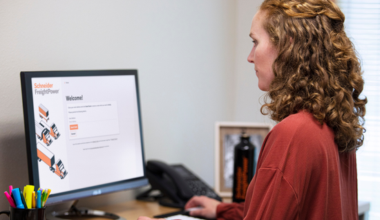 Person working at computer displaying Schneider FreightPower welcome screen