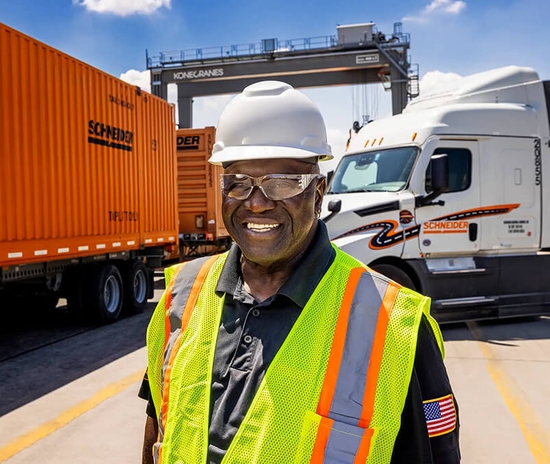 Intermodal driver standing in front of Schneider intermodal container and Schneider tractor