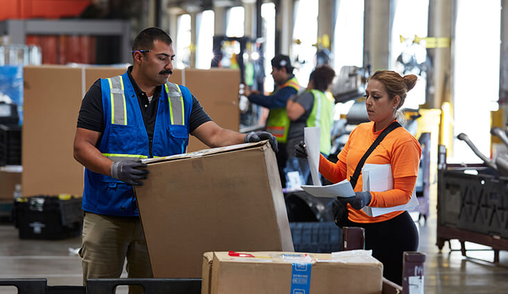 Two people in a warehouse working with boxed shipments