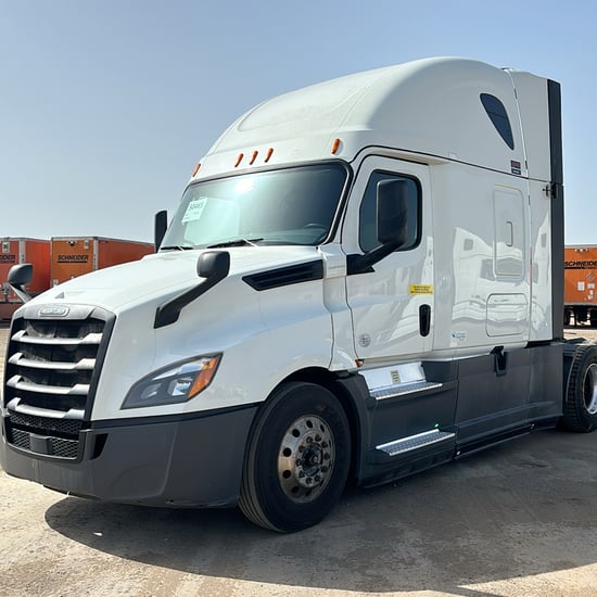 a white semi-truck tractor parked in front of a row of orange Schneider trailers