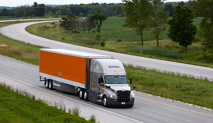 Full van truckload truck pulling orange trailer driving on highway
