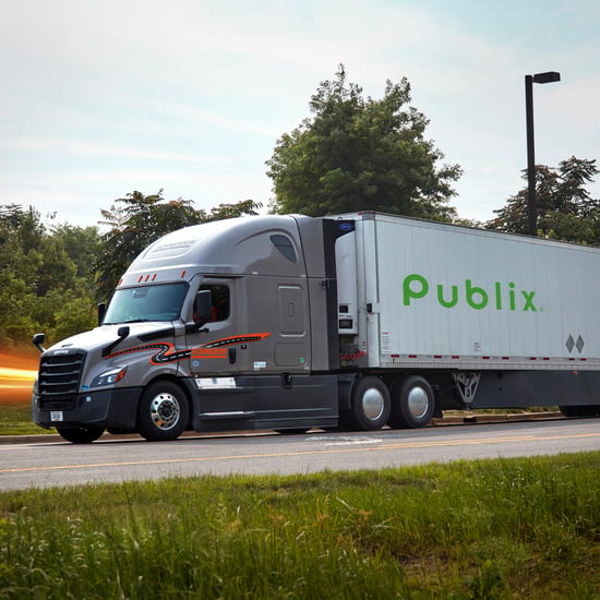 A large semi-truck on the road, with trees lining the highway under a clear sky