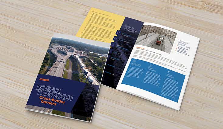 cross border brochure opened up on light wood surface