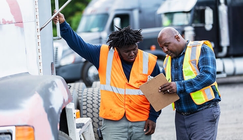 two men looking at a clipboard in a truck lot