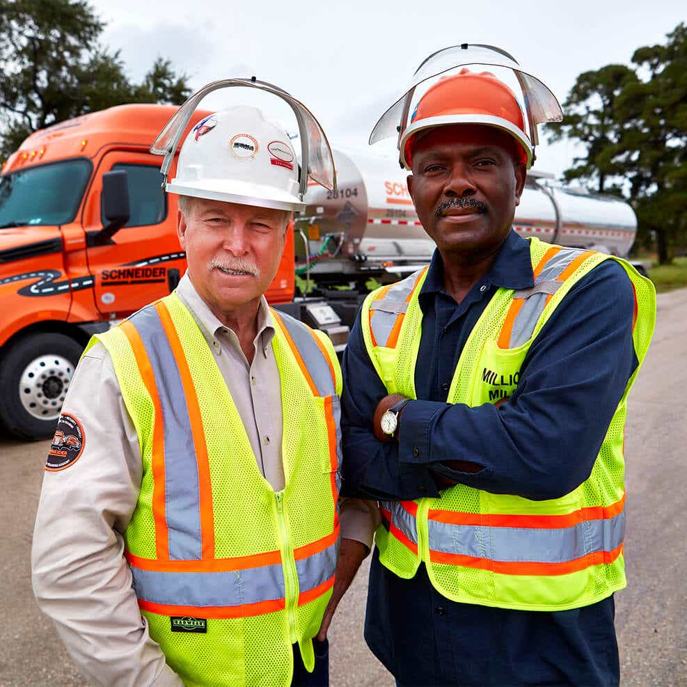 Two drivers standing in front of a bulk truck and trailer