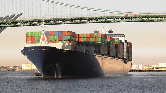 cargo_insurance_hero.jpg A cargo ship under a bridge transporting goods and materials.