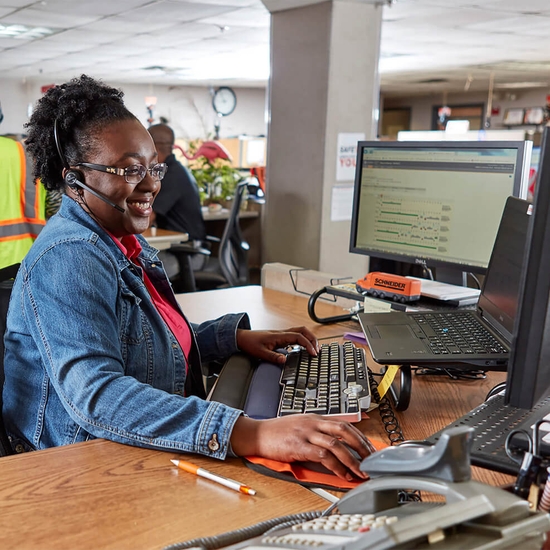Schneider team member on phone in front of computer providing customer full visibility into