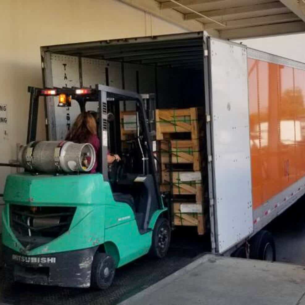 A warehouse associate unloading a charity delivery made by a Schneider driver at no-cost