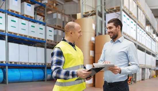 Two business professionals standing in a warehouse of paper products, discussing the next shipment