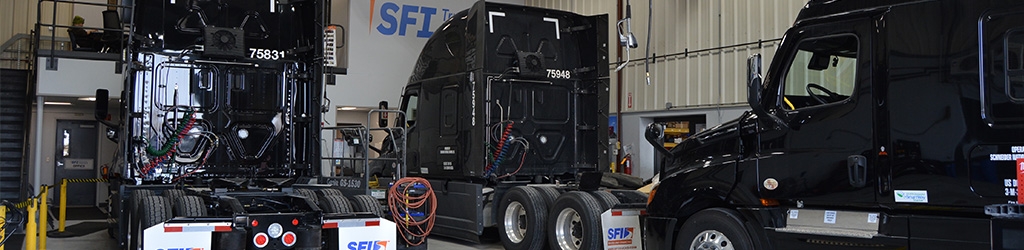Three trucks parked in a maintenance shop