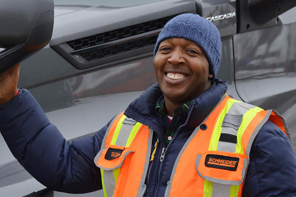 Owner-operator William McKindra smiling while posing in front of his truck