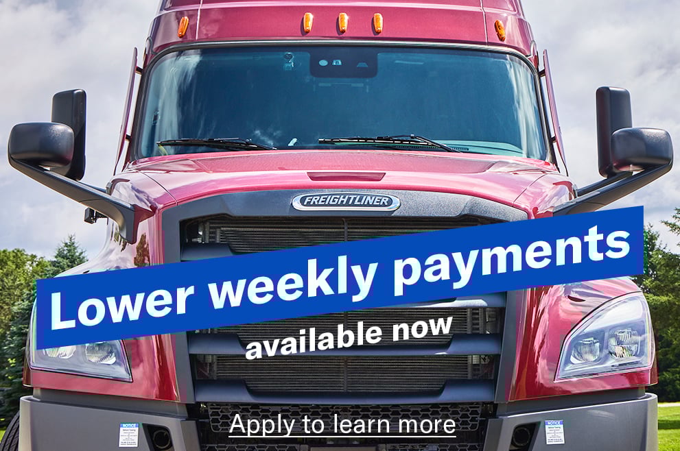 A closeup ground level shot of a red Freightliner Cascadia with the words "Lower weekly payments available now" angled across the grill and a link reading "Apply to learn more"