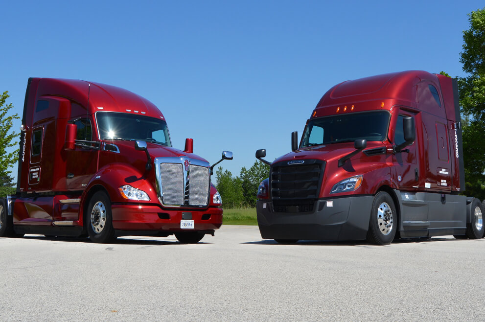 two red semi trucks parked next to each other ready to be leased.