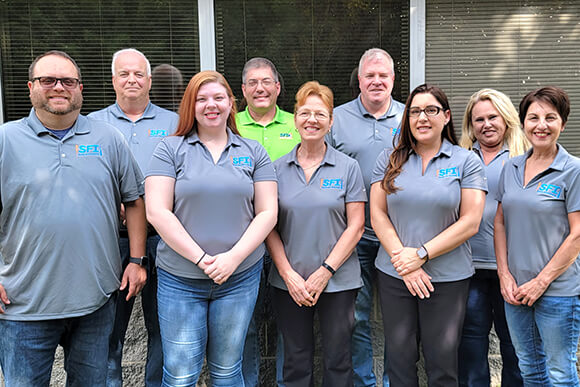 A group of people in SFI polo shirts, standing outdoors.