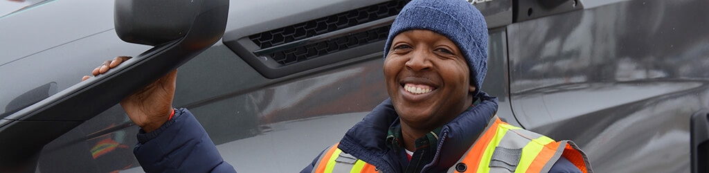 Owner-operator William McKindra smiling while posing in front of his truck