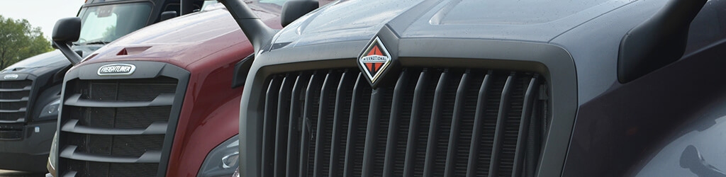 Close up of the grill of International and Freightliner semi trucks 
