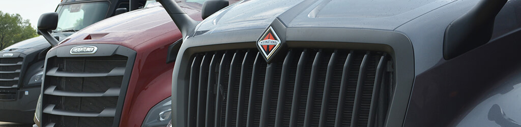 Close up of the grill of International and Freightliner semi trucks