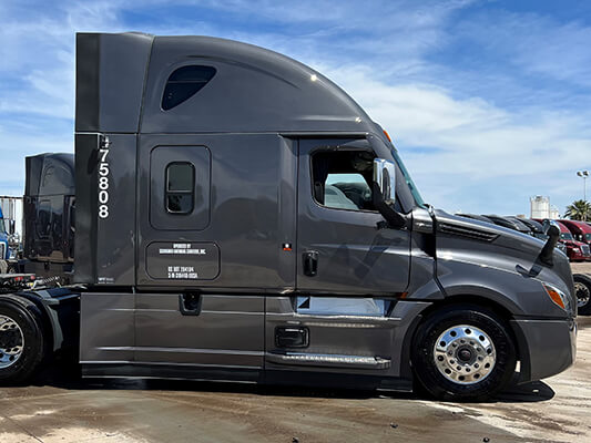 The passenger side of a charcoal 2024 Premium Freightliner Cascadia semi truck