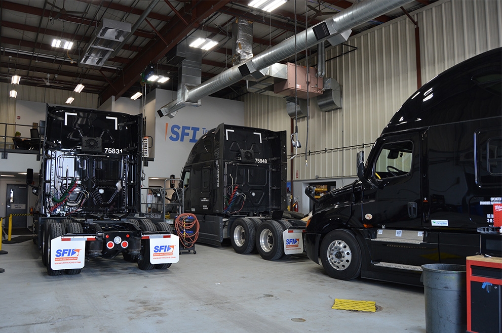Three trucks parked in a maintenance shop