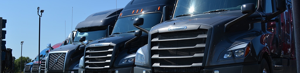 A row of Freightliner and Volvo trucks available for lease at SFI