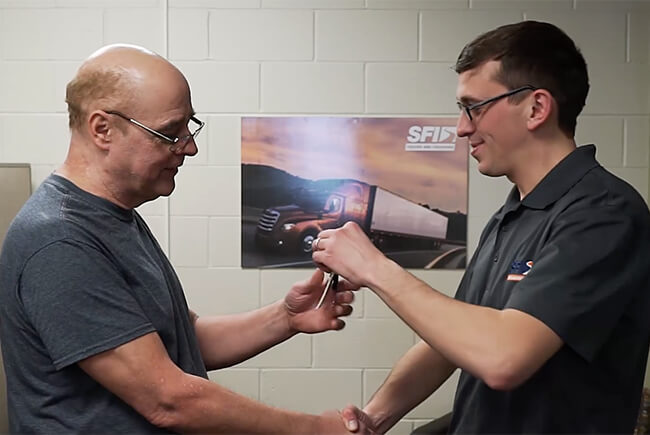 An Account Administrator shakes a client's hand while handing him the keys to his truck