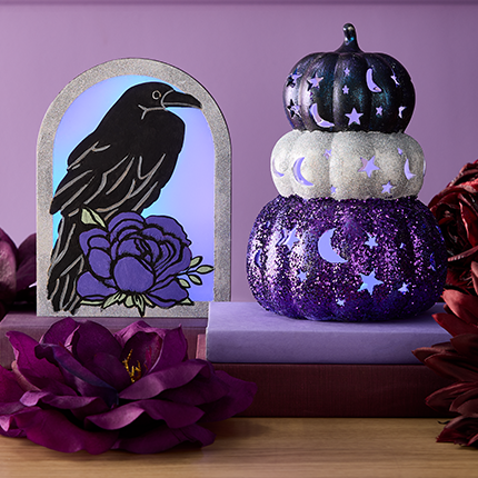 black crow craft and stack of black, white and purple craft pumpkins