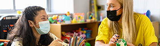 woman and child with face masks crafting in play room
