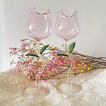 pink tulip shaped wine glasses with pink flowers in the background