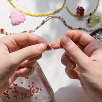hands creating a bead necklace