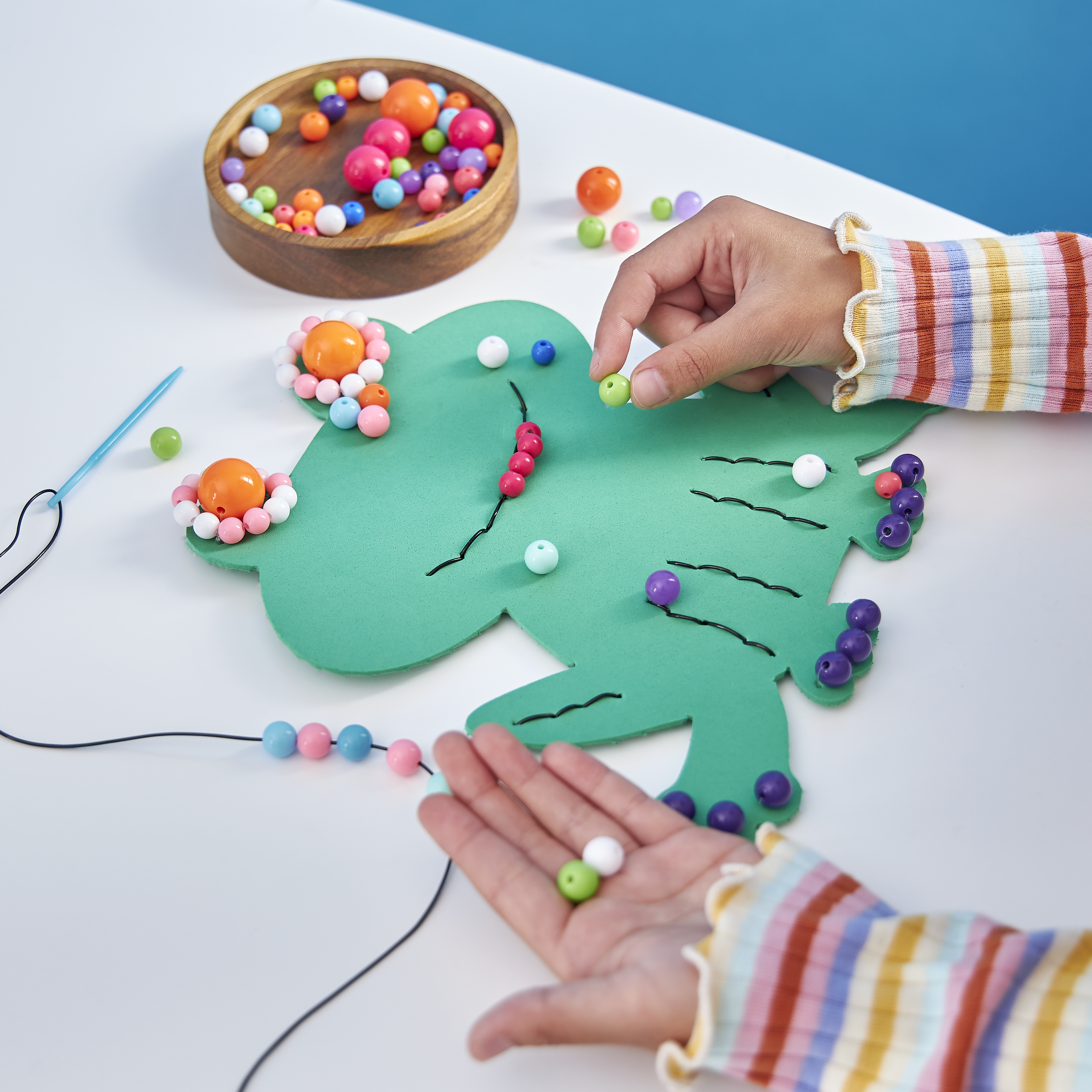 A child places beads on a paper frog