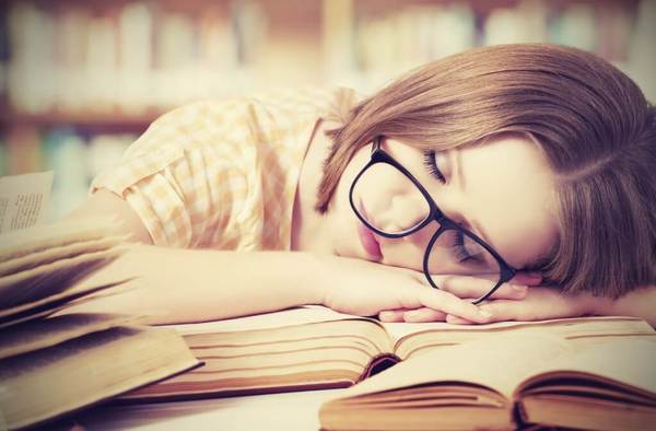 student_sleeping_on_a_book_in_the_library.jpg