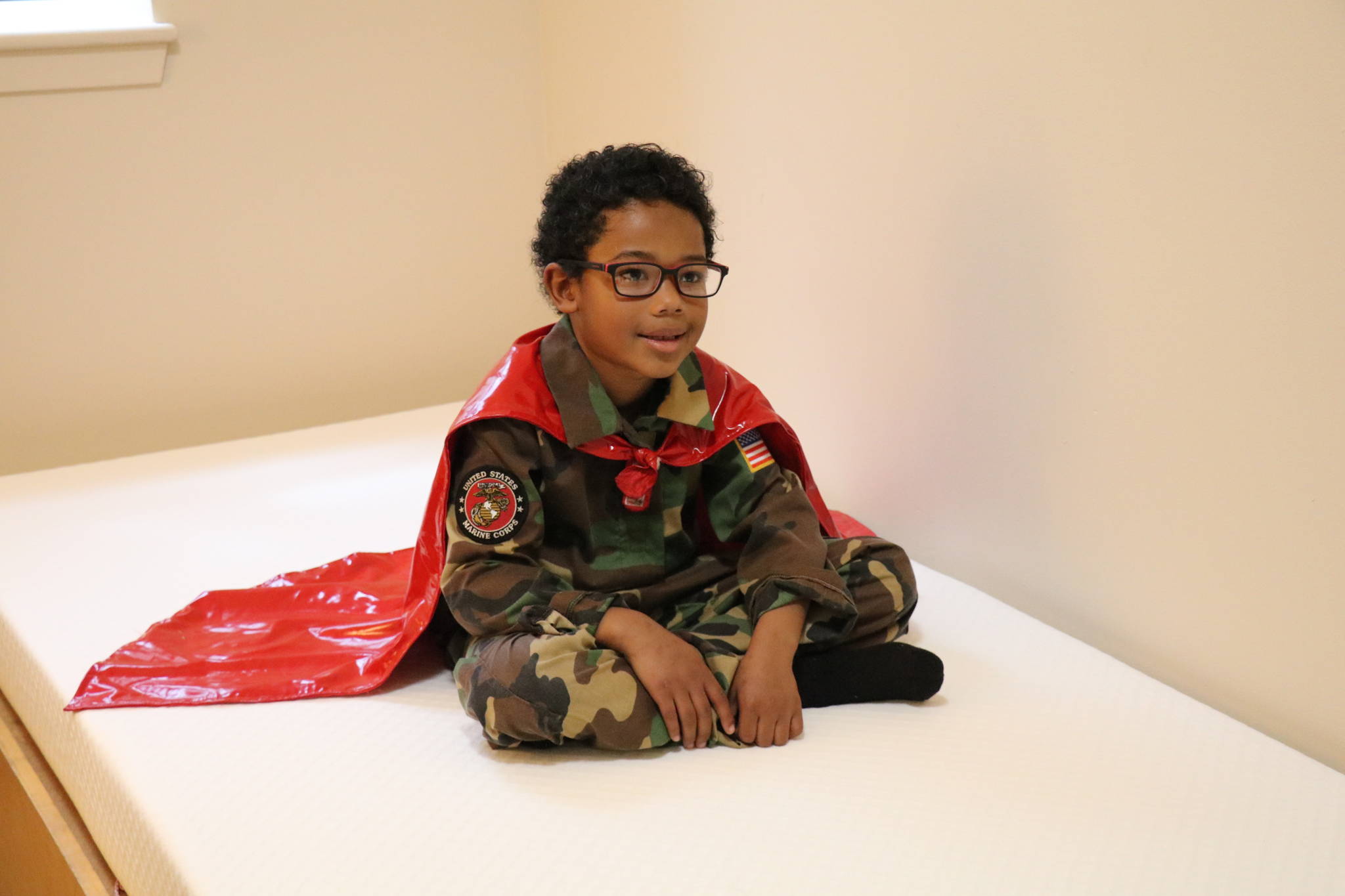 Child with a superman cape sitting on a Leesa mattress