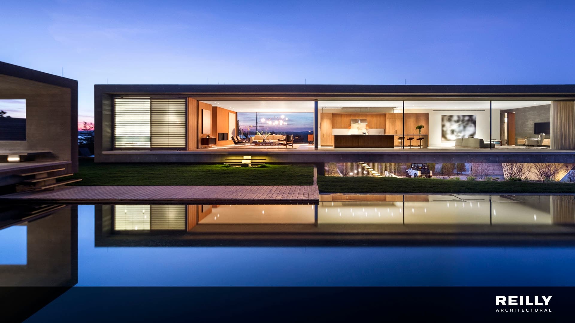 contemporary home with glass walls behind a large infinity pool reflecting the home