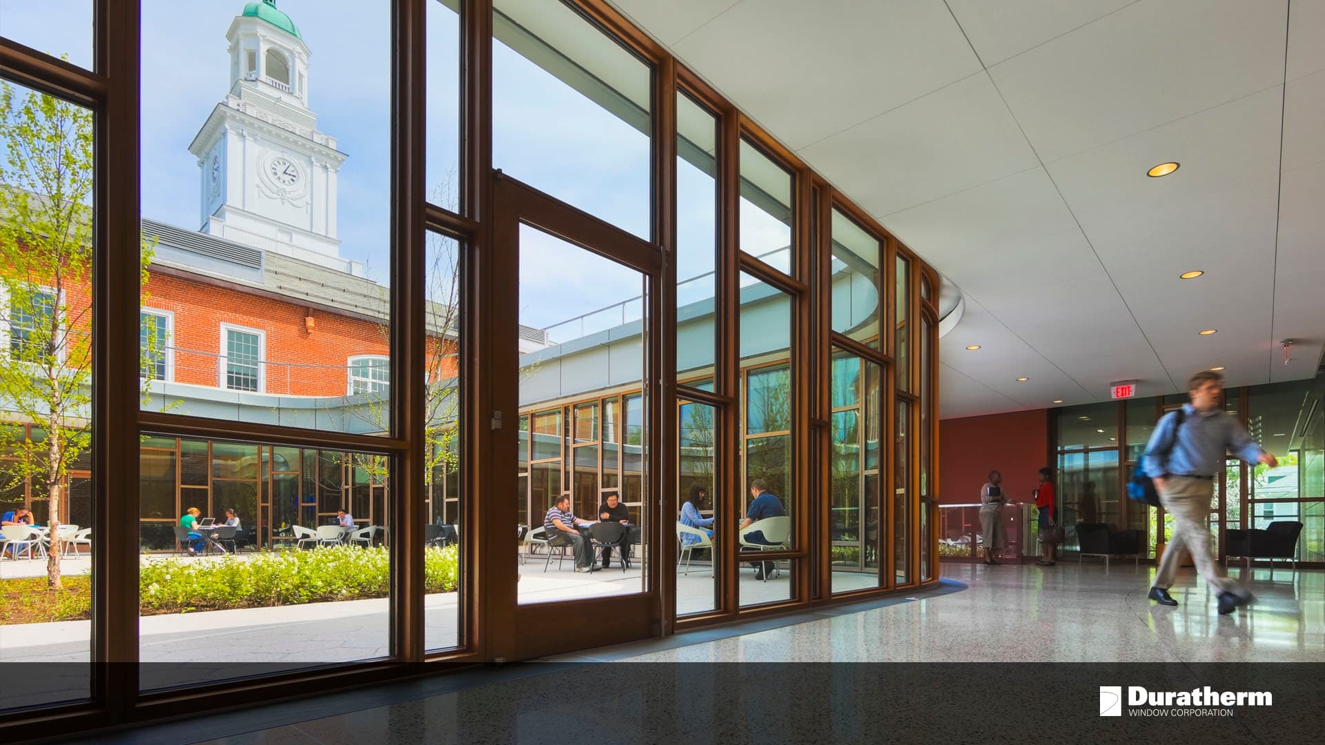 the interior of a college hallway with floor-to-ceiling windows and doors