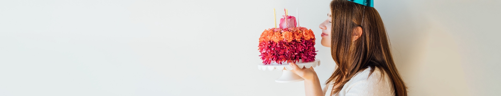 Woman holds birthday flower cake up to her nose to smell flowers