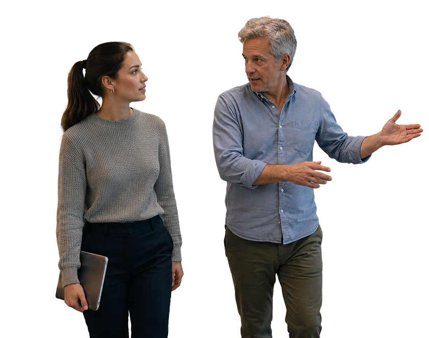 Two coworkers walking and talking in a modern office hallway.