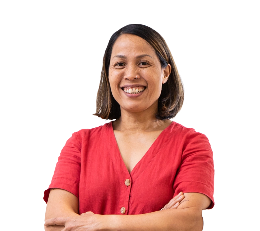 The owner of a Thai restaurant smiles as she leans against a shelf with her arms crossed