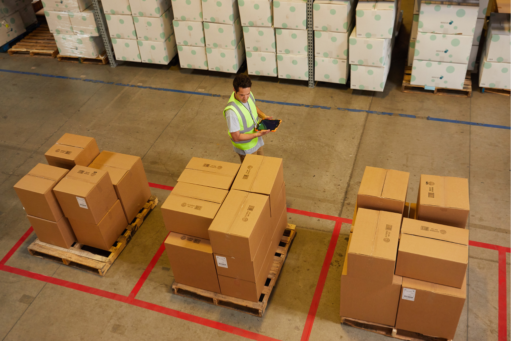 A male warehouse worker taking inventory of boxed goods