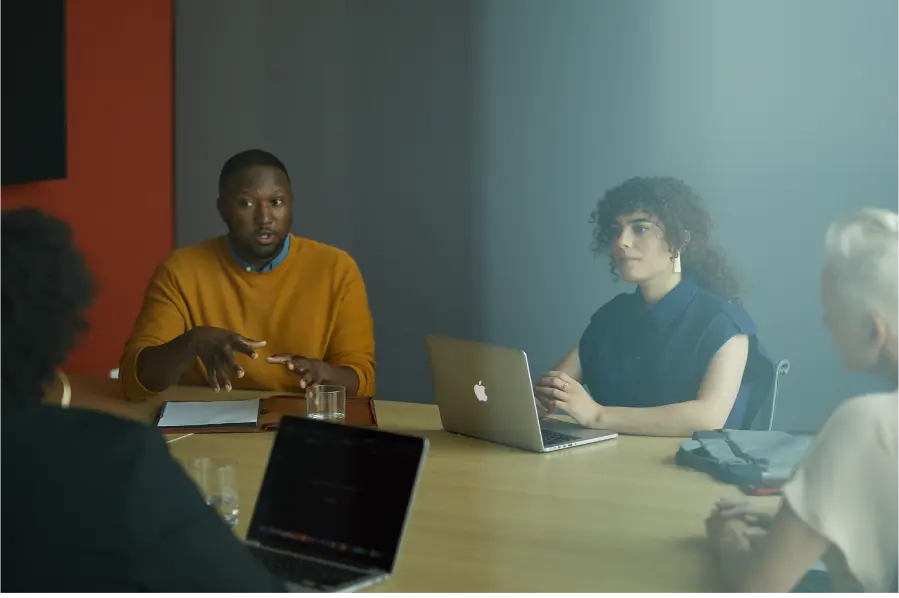the man sits in a meeting room with coworkers and talks