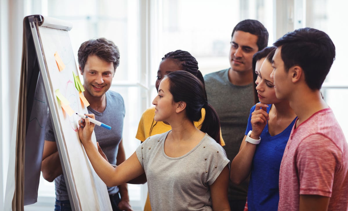 Students standing next to their instructor who is writing something on a whiteboard during a Korean lesson at Berlitz France