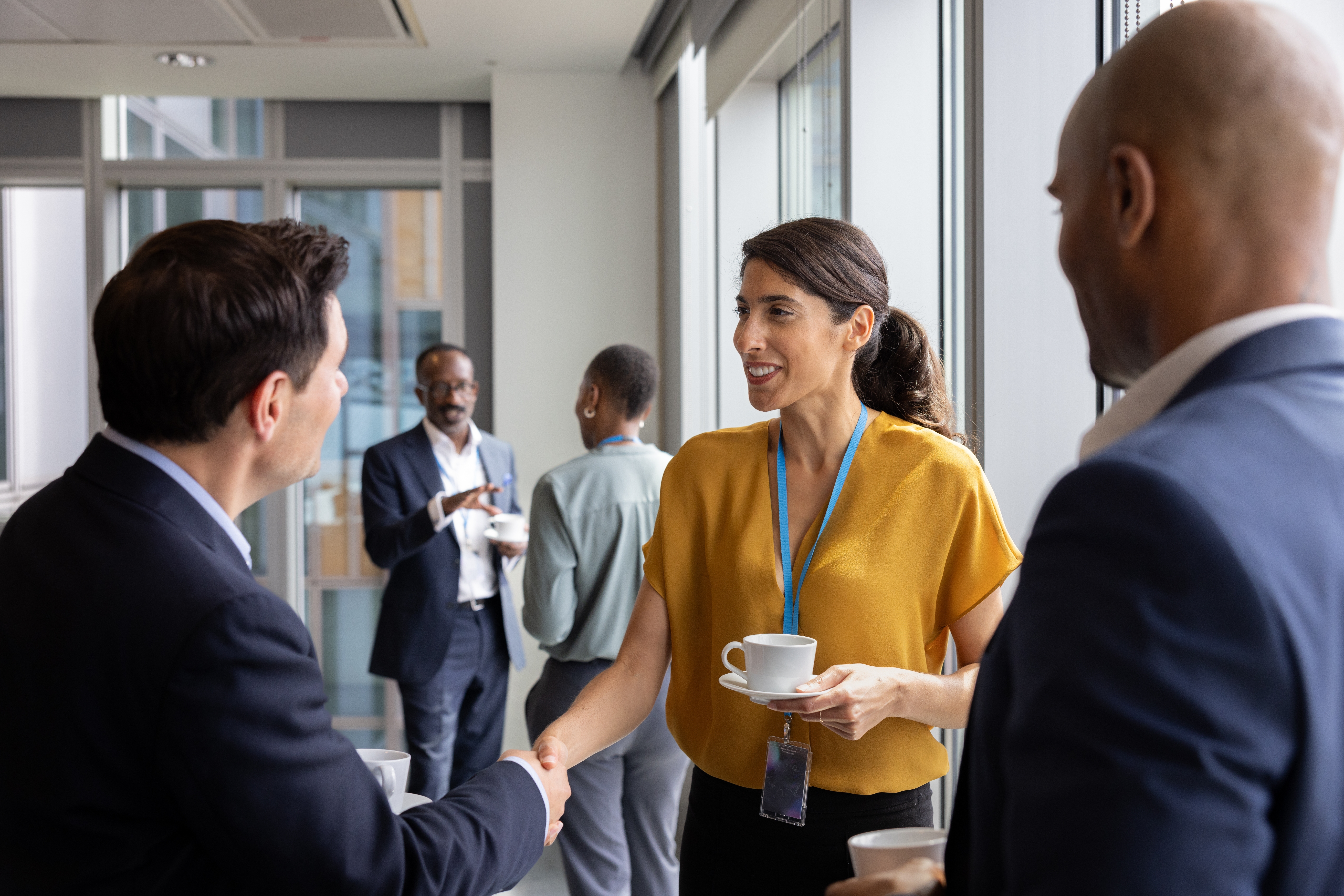 Femme d'affaires serrant la main de ses clients et discutant avec eux après avoir suivi un formation management interculturel avec Berlitz France.