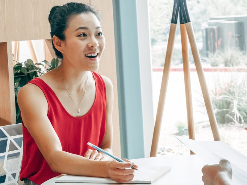 Femme avec un carnet de notes écrivant les adjectifs en anglais qu'elle vient d'apprendre dans un cours de langue