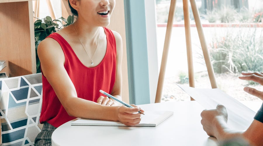 Femme avec un carnet de notes écrivant les adjectifs en anglais qu'elle vient d'apprendre dans un cours de langue