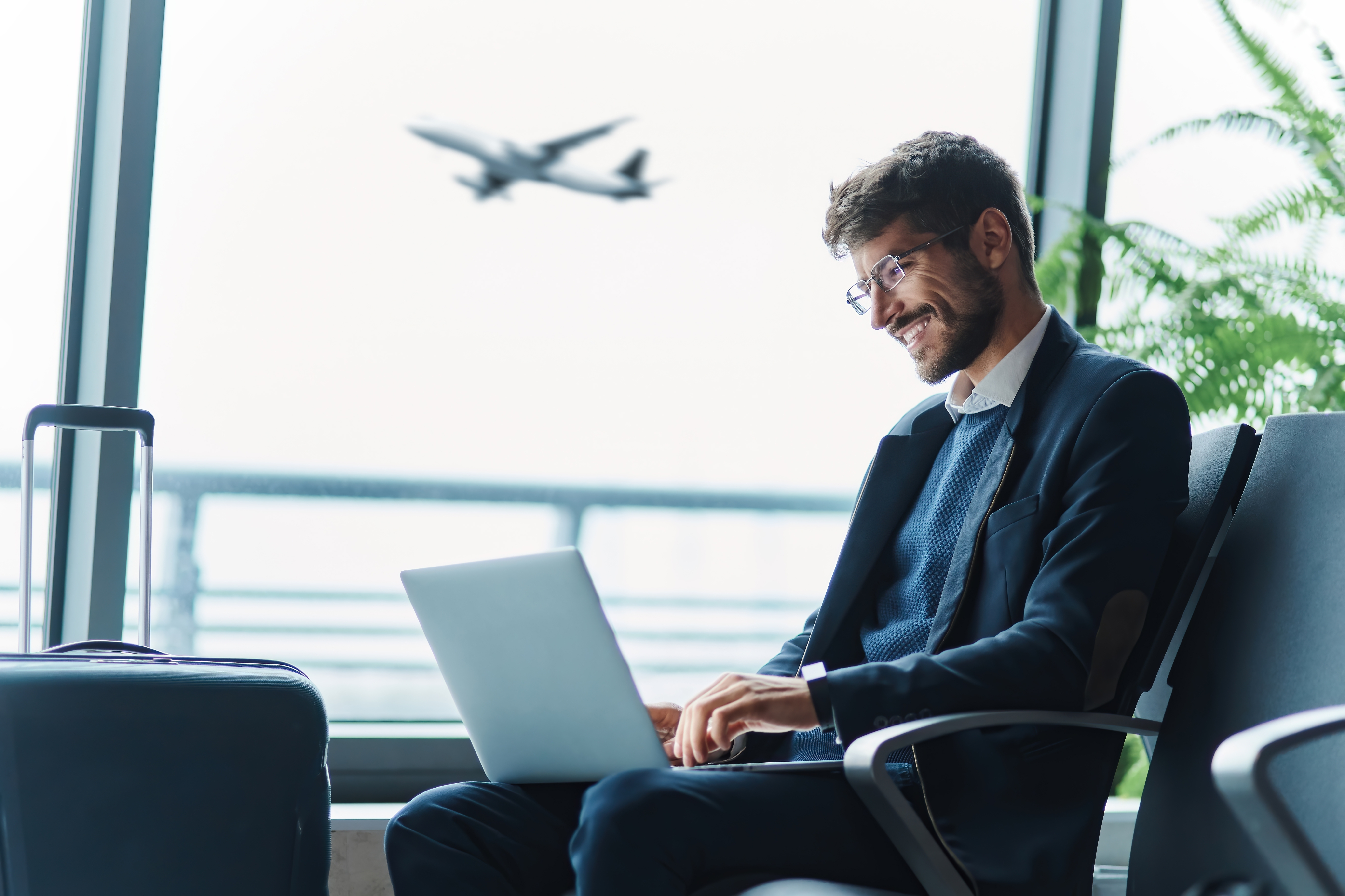 Man at the airport with a laptop enhancing his professional language skills online with MyBerlitz Industry Tutor