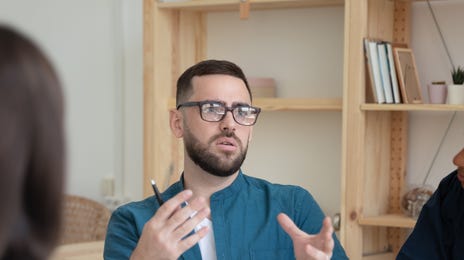 L'élève s'assoit à une table à côté de ses camarades de classe et leur parle dans leur langue cible dans le cadre de leurs cours de langue en groupe.