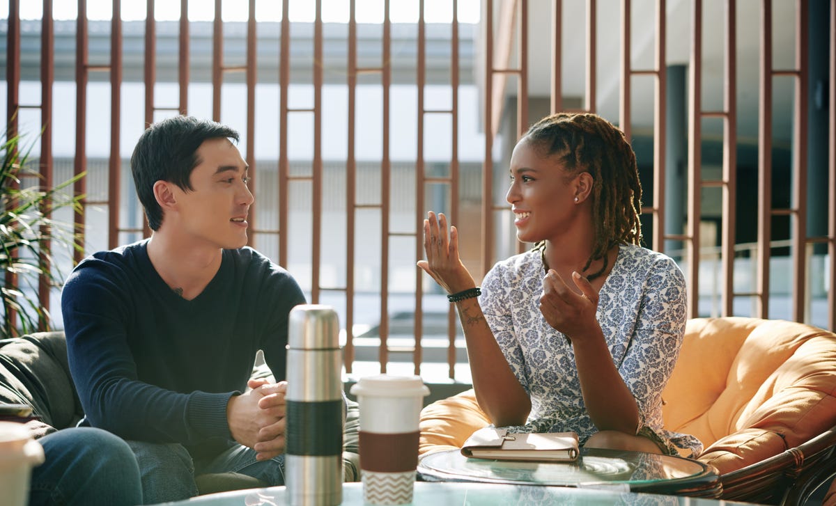 L'étudiant et le professeur sont assis l'un à côté de l'autre et se parlent pendant l'apprentissage d'une langue étrangère.