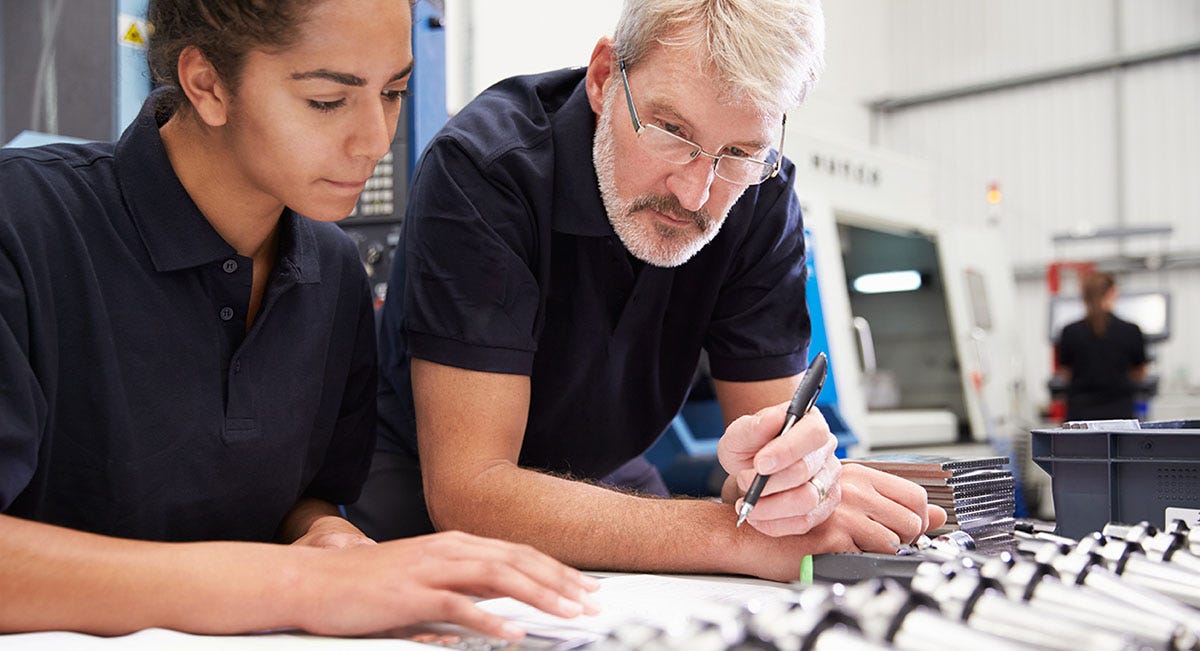 Man holding a pen talking to a woman and teaching her about accounting