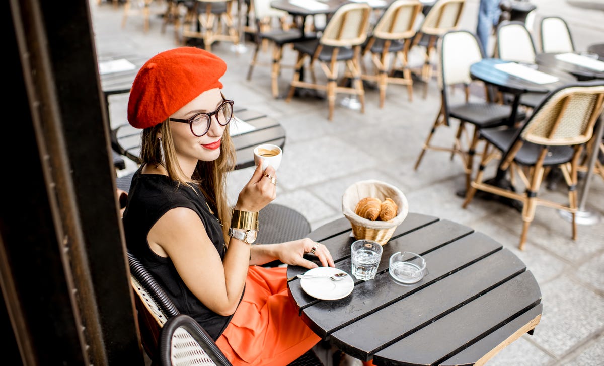 Femme assise à l'extérieur d'un café en train de boire un café après sa le cours de chinois avec Berlitz France.