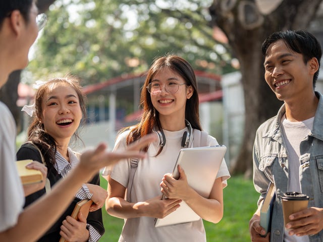 Groupe d'adolescents discutant et riant à l'extérieur avant leur cours avec Berlitz où ils apprennent l'espagnol pour les adolescents.