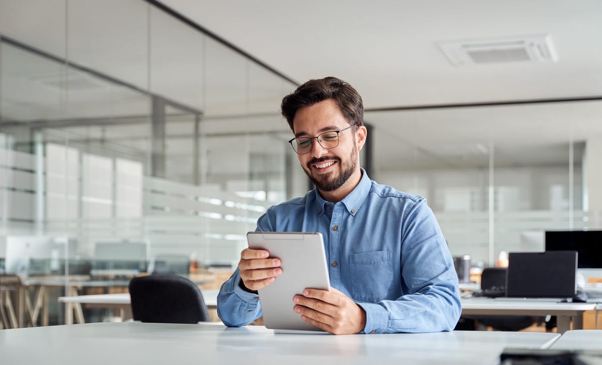 Homme tenant une tablette et lisant des informations sur les cours de langue subventionnés par Berlitz